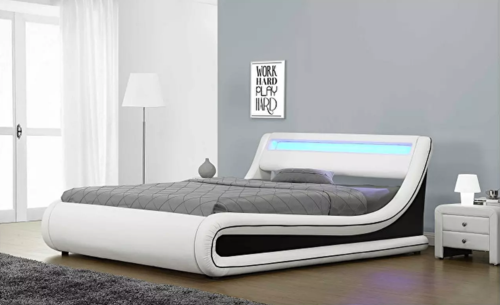 Moderan bračni krevet s podnicom i prostorom za odlaganje u kombinaciji crno-bijele eko-kože. RGB LED rasvjeta pridonosi ravnoteži prostora.