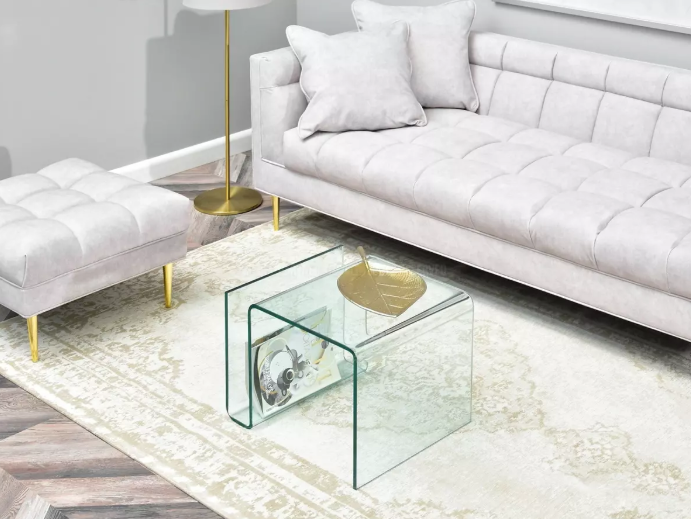 Sigurnost i stabilnost namještaja: Moderan interijer s baršunastom, svijetlo sivom sofom, tabureom, staklenim stolićima i zlatnim detaljima.