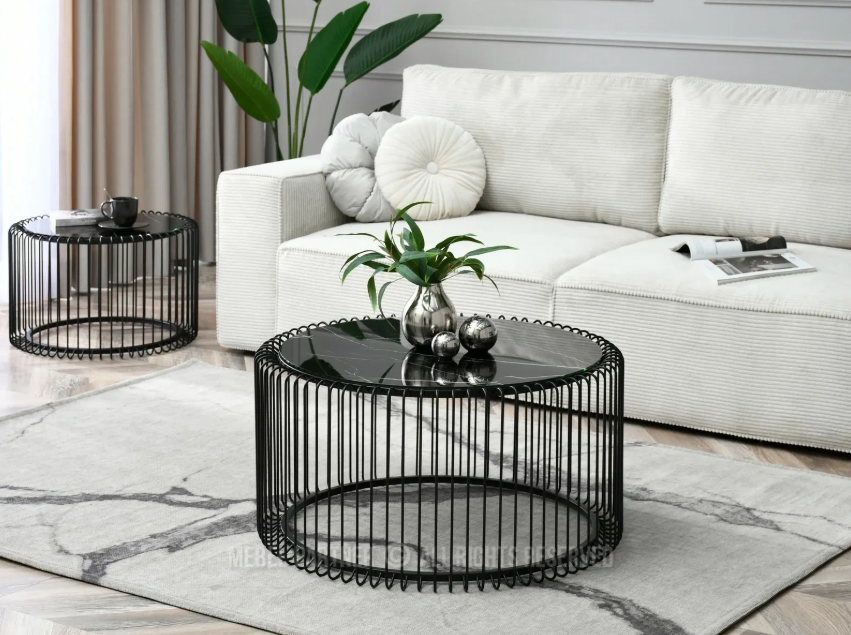 Okrugli, crni metalni stolići s mramornom pločom, smješteni ispred bijele sofe u modernom dnevnom boravku.