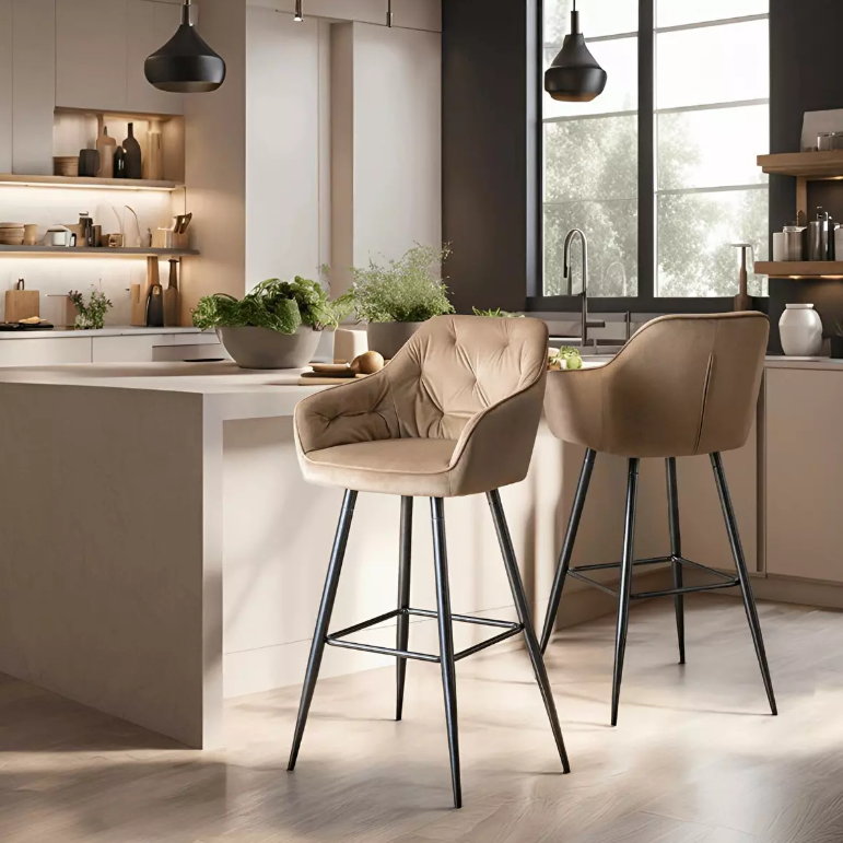 Dvije elegantne barske stolice s bež tapeciranim sjedištem i naslonom smještene uz moderan kuhinjski otok u svijetlom interijeru.