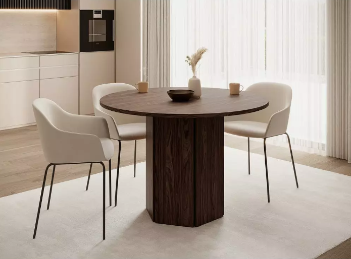 Okrugli blagovaonski stol od tamnog drva s tri moderne stolice u svijetloj blagovaonici.