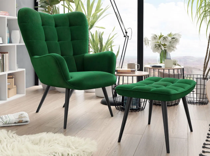 Udobna, visoka fotelja i pripadajući tabure presvučeni tamnozelenim baršunom, u modernom dnevnom boravku.